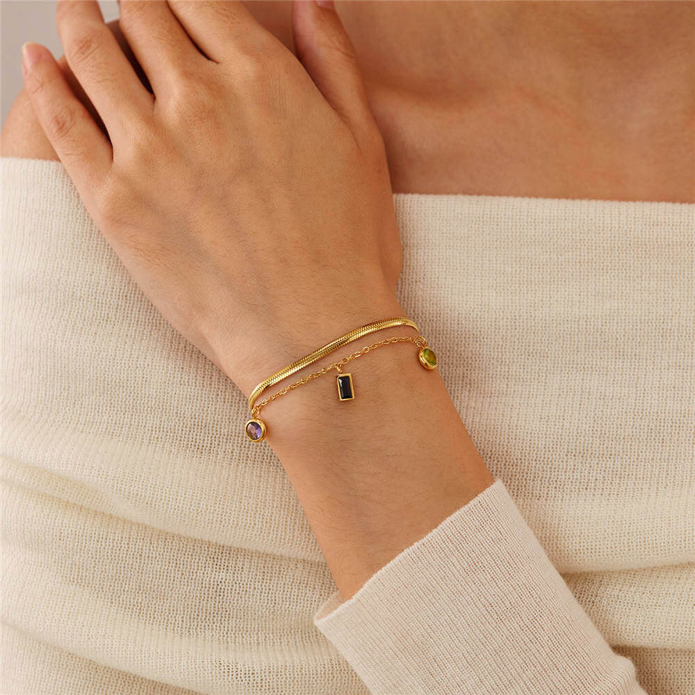 Multi-Charm Chain Bracelet with charms on a wrist against a beige background