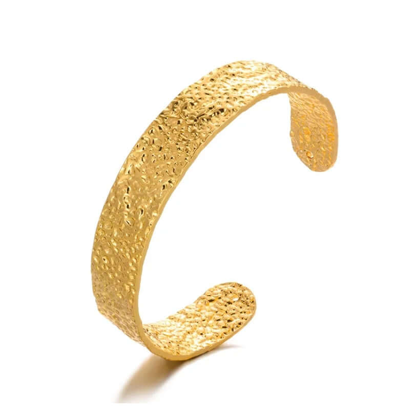 Gold textured braceletl against a white background