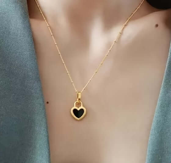 Gold necklace with black heart pendant on a woman's neck, elegant hypoallergenic jewelry
