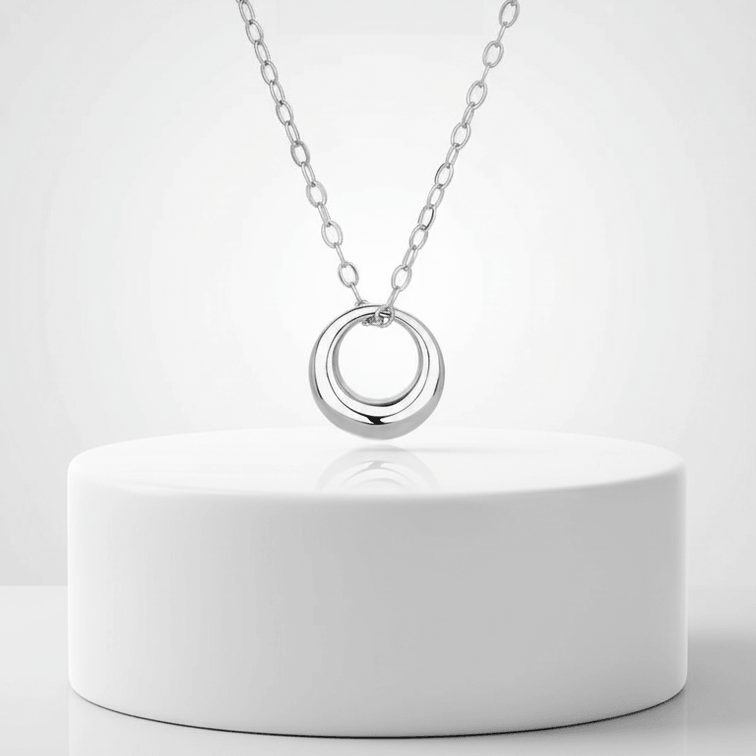 Mini Gold Circle Pendant Necklace on a sleek silver chain displaying a modern design on a minimalist background.
