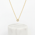 Single Diamond Necklace Gold on white marble pedestal 