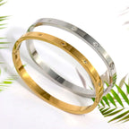 Ceyrah gold and silver Star Zirconia Bangle Bracelet on white background with green leaves
