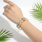 Ceyrah gold and silver Star Zirconia Bangle Bracelet on wrist, tropical leaf background