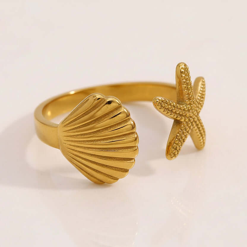Starfish & Shell Open Ring Gold with starfish and fish design on a beige stone surface