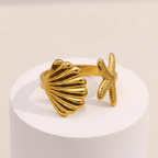 Starfish & Shell Open Ring Gold on a white pedestal against a beige background