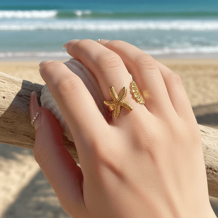 Hand wearing gold Starfish & Shell Open Ring Gold on a beach