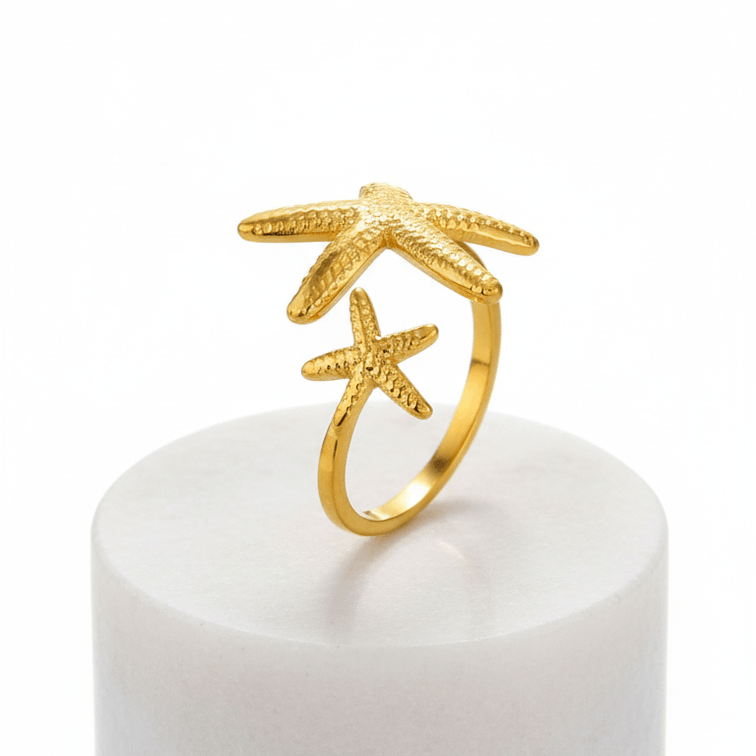 Twin Starfish Open Gold Ring with star design on a white marble block