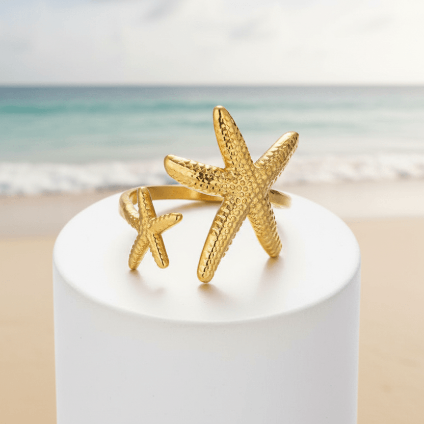 Twin Starfish Open Gold Ring on a white pedestal against a white background