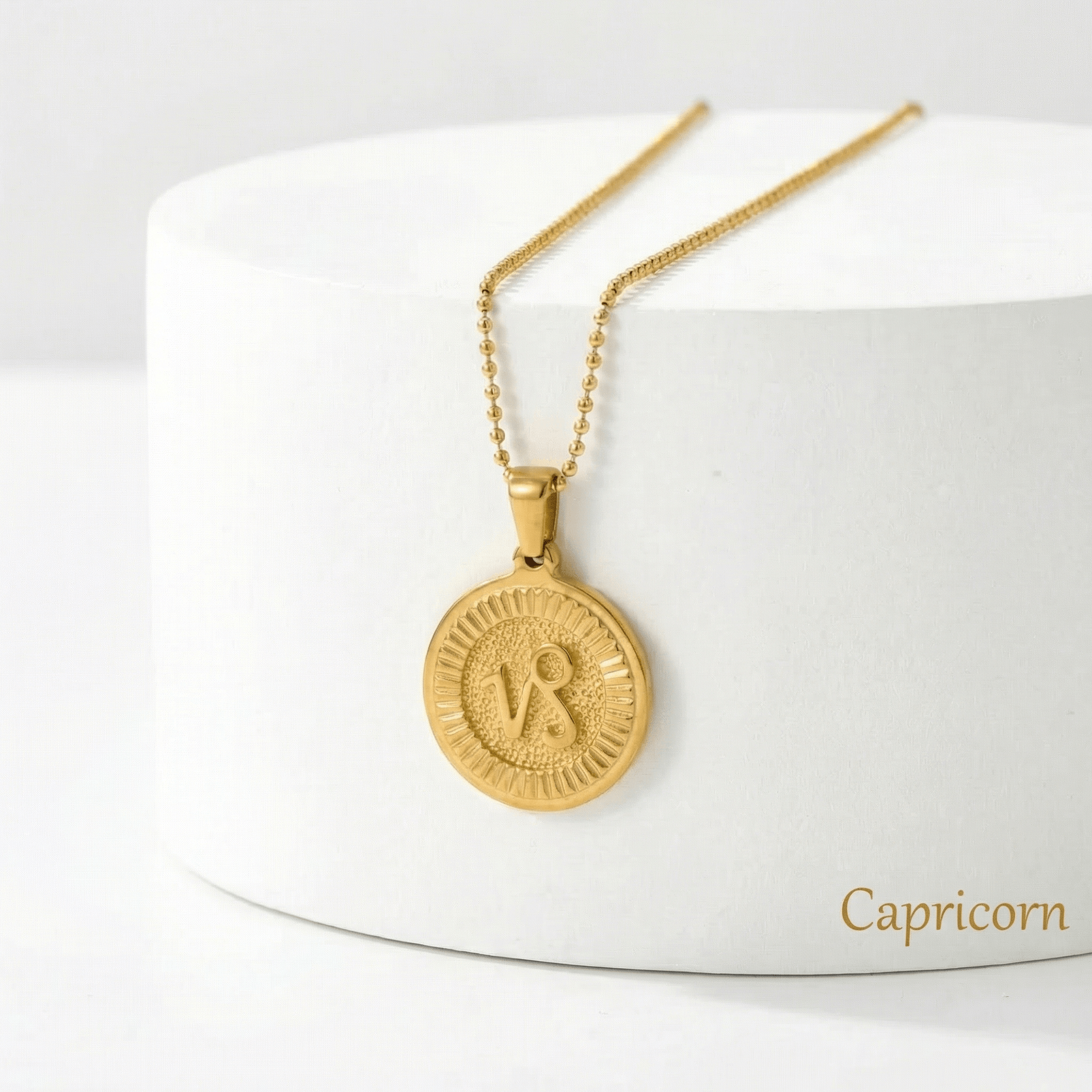 Zodiac Sign Medallion Necklace Gold with a Capricorn pendant on a white stand
