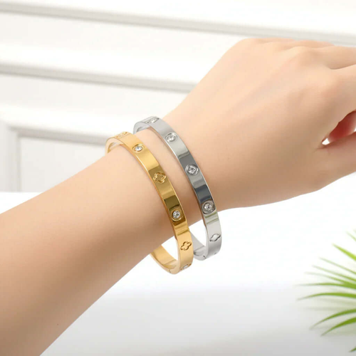 Hand wearing gold and silver Ceyrah clover engraved diamond bangle bracelet.