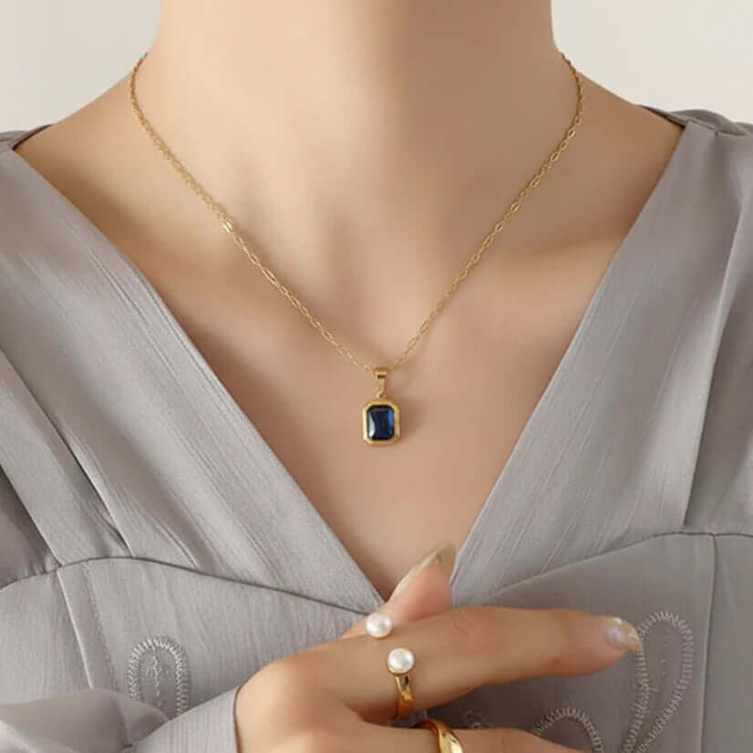 Elegant woman wearing gold blue stone pendant necklace from Ceyrah.