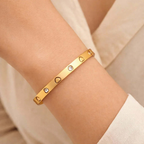 Gold heart engraved bangle bracelet on wrist, Ceyrah jewelry